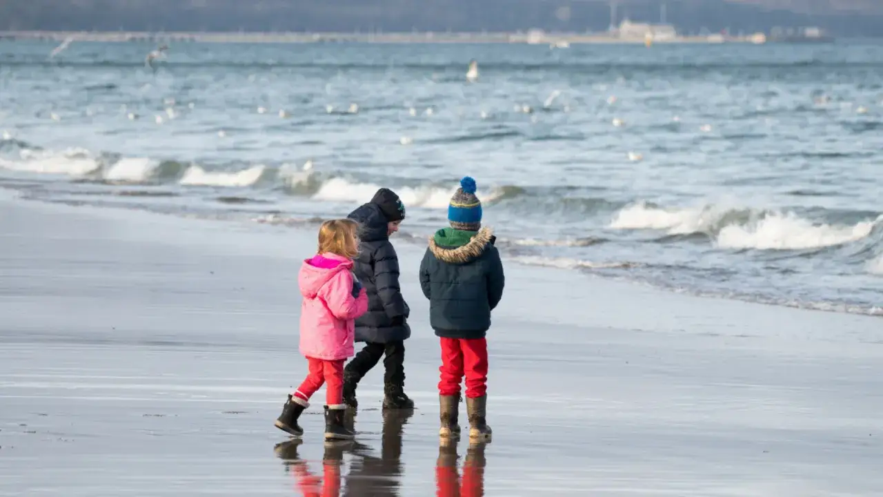 Rodzina spacerująca zimą po plaży Bałtyku